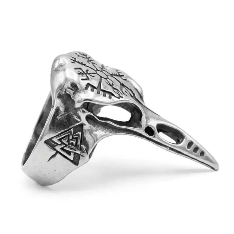 Oxidized pewter ring cast as a detailed raven skull with a long tapered beak extending down the finger, engraved with a Valknut symbol of three interlocking triangles near the band.