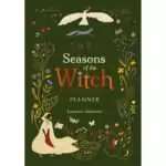 Green cover of the 2027 Seasons of the Witch Planner by Lorriane Anderson, with a hooded woman holding an open book, a white bird, a fox, moths and wildflowers around the title.