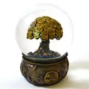 Money tree water globe: a clear sphere with glitter around a gold-toned tree of overlapping coins, on a bronze-toned base wrapped in gold rope with ingots and a coin medallion.
