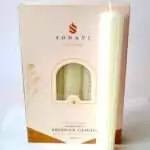 Cream-white 8 inch hand-rolled honeycomb beeswax candle with a white wick standing in front of its cream box marked Natural Beeswax Hand Roll Beeswax Candle, Pack of 5